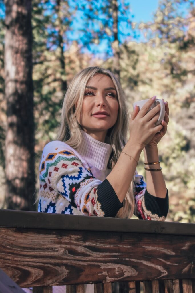 woman in white and blue sweater covering her face with her hands